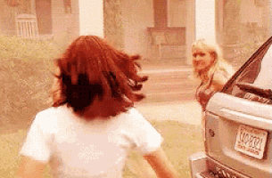 a woman is running towards a car while another woman stands behind her .