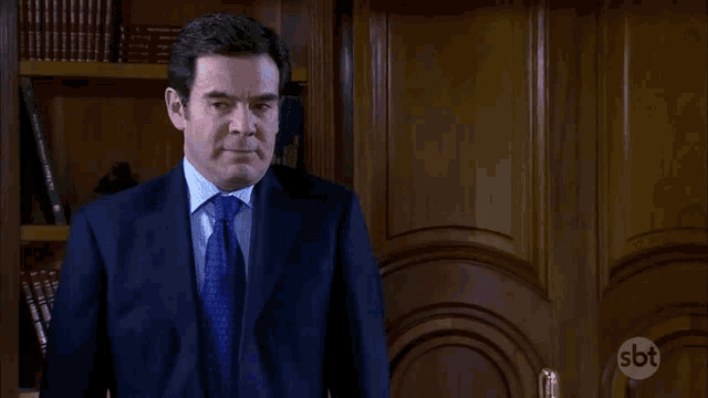 a man in a suit and tie is standing in front of a door that says sbt on it