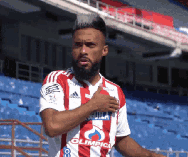 a soccer player in a red and white uniform with the word olimpica on it