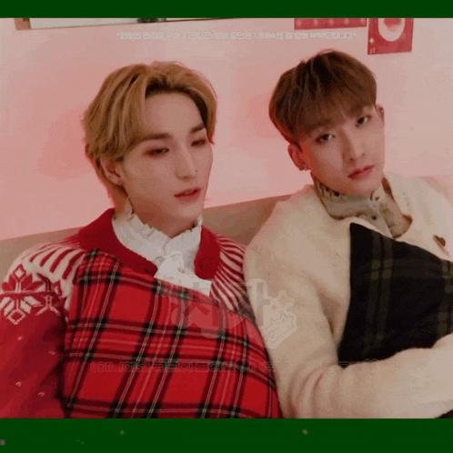 two young men are sitting next to each other and one of them is wearing a red and white plaid sweater