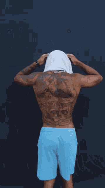 a shirtless man with a towel around his neck wearing supreme shorts