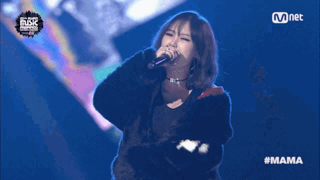 a woman singing into a microphone with the hashtag #mama on the screen