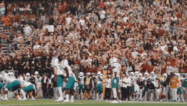 a football game is being played in front of a crowd with a sign in the stands that says no smoking