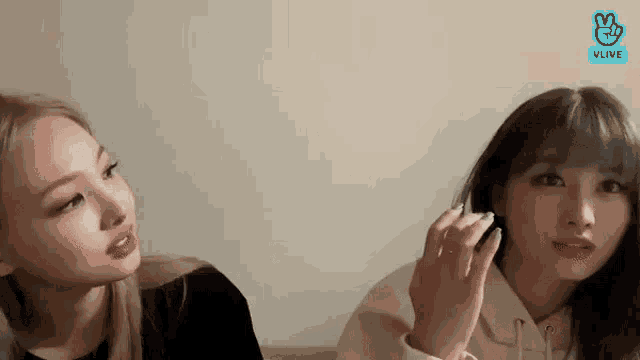 two girls are sitting next to each other on a couch and talking .