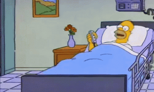 homer simpson is laying in a hospital bed holding a phone