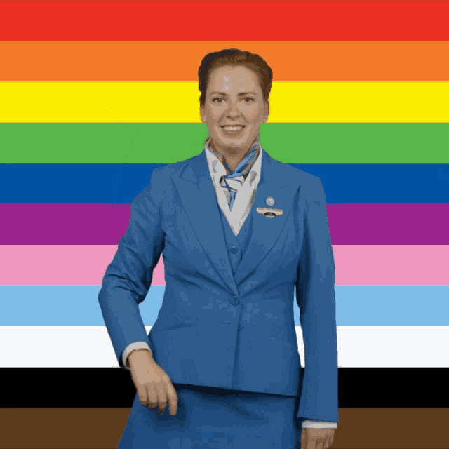a woman in a blue suit is smiling in front of a rainbow colored background