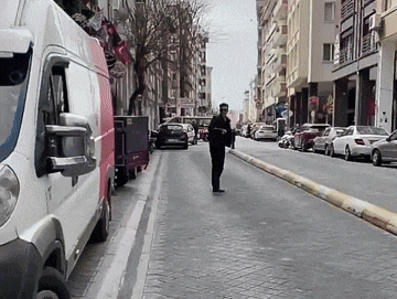 a man walking down a street with a white van that says ' a ' on the side