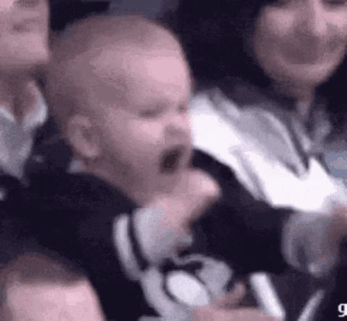 a baby is crying in a crowd of people at a game .
