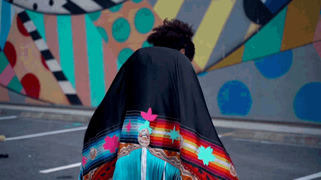 a person wearing a colorful blanket in front of a wall