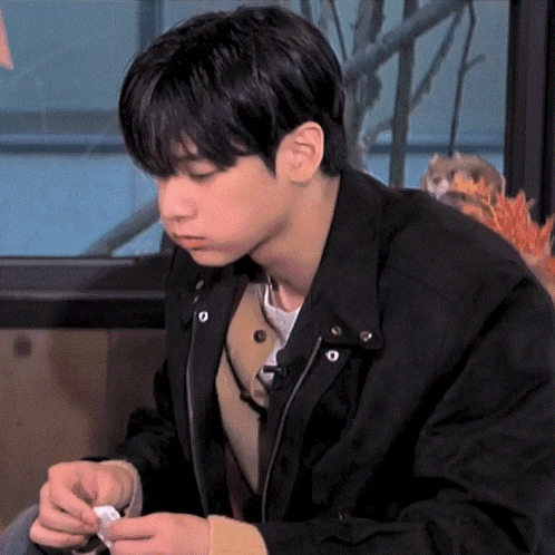 a young man in a black jacket is looking at something
