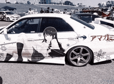 a white car with a picture of a girl on the side is parked in a parking lot