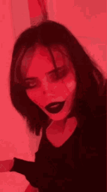 a woman is wearing a devil costume with black lipstick and a choker .