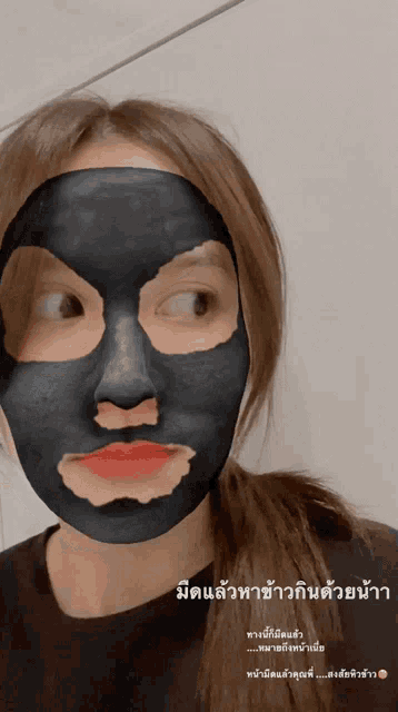 a woman wearing a black face mask with foreign writing on the bottom right