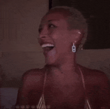 a woman with a tattoo on her wrist is smiling while wearing a bikini top .