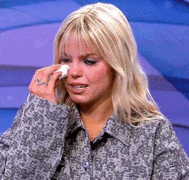 a woman wipes her face with a tissue while wearing a ring on her finger
