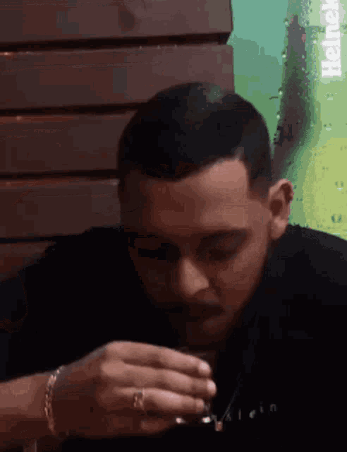 a man is drinking from a glass with the word klein on it