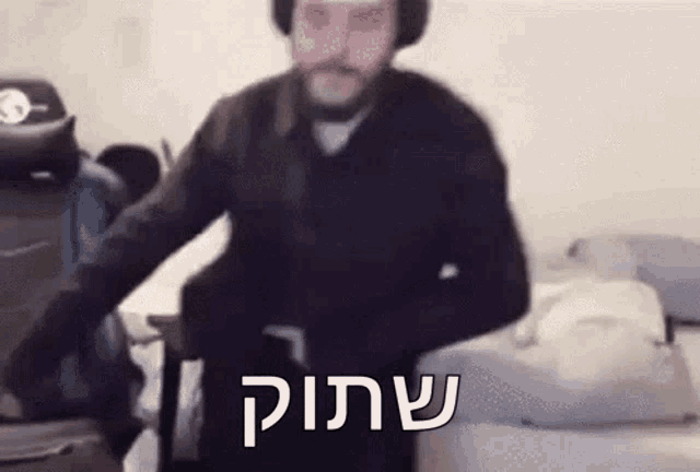a man with a beard and headphones is standing in a room with a suitcase in his hand .