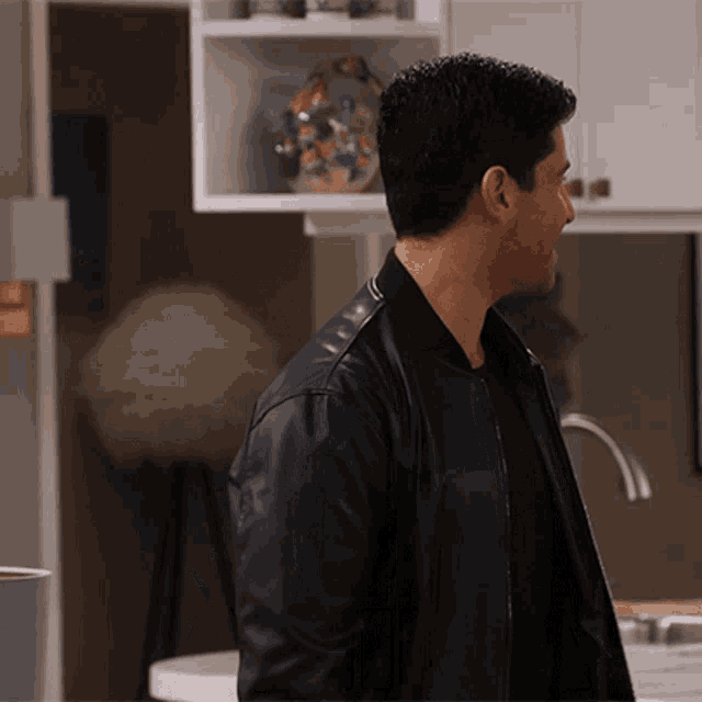 a man in a black leather jacket stands in front of a sink