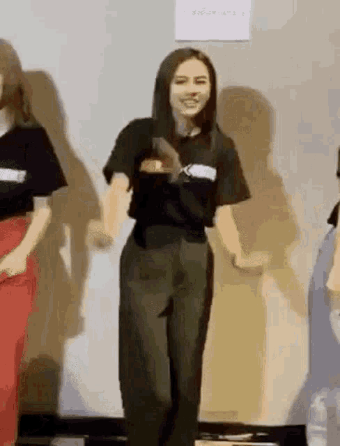 a woman in a black shirt and green pants is dancing in a room .