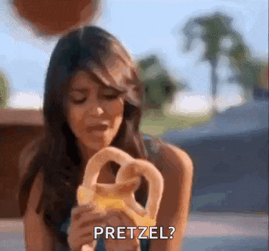 a woman is holding a pretzel in her hand and asking if it is pretzel .
