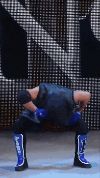 a wrestler in a black vest and blue boots with the number 1 on them