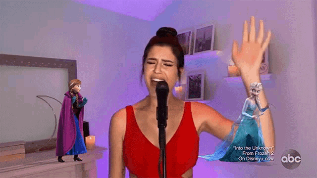 a woman singing into a microphone in front of a frozen 2 poster
