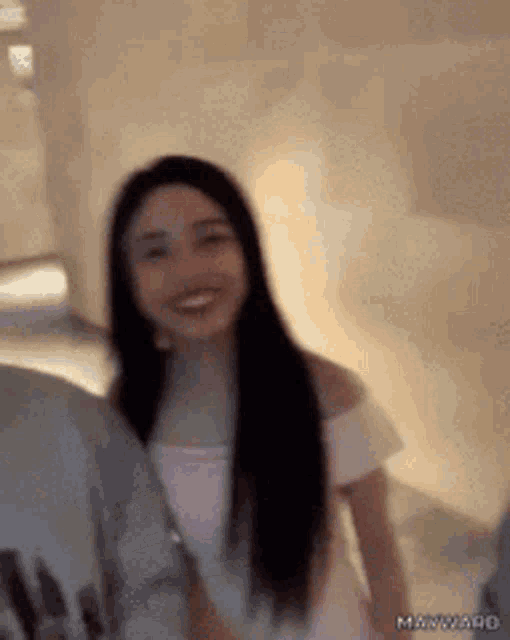 a woman with long black hair is smiling while standing next to a man in a grey shirt .