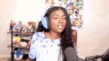 a woman wearing headphones and a tie dye shirt is sitting in front of a microphone .