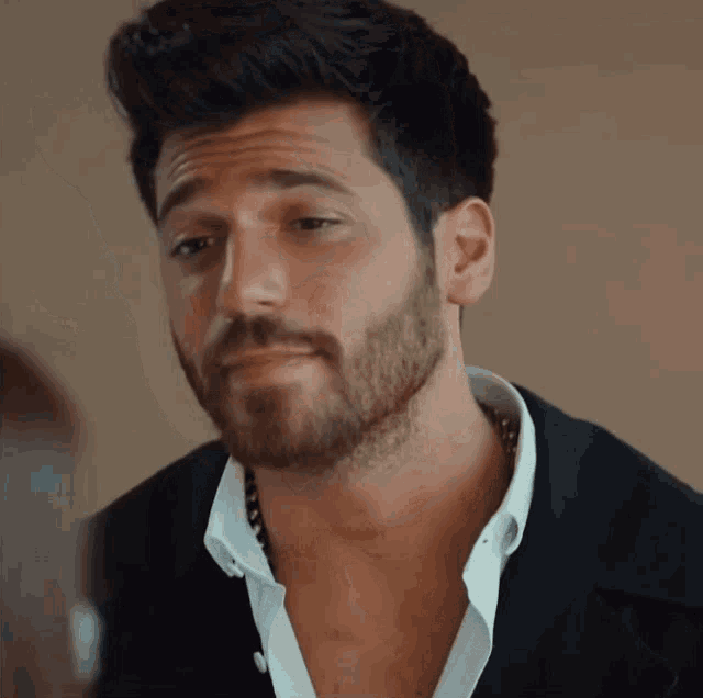 a man with a beard wearing a white shirt and black jacket