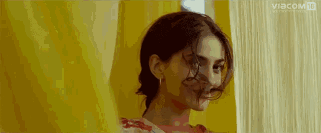 a woman is standing in front of a yellow curtain with the word viacom on the bottom