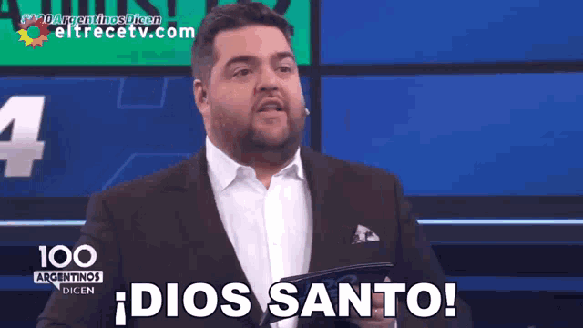 a man in a suit says dios santo on a screen