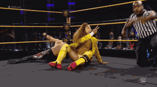 a wrestler in a yellow suit is laying on the ground
