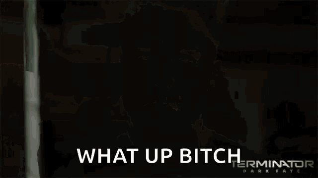 a woman in a black shirt is standing in front of a sign that says " what up bitch "