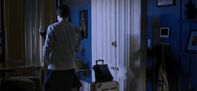 a man and woman hugging in a dark room with a suitcase and a bag with the letter b on it