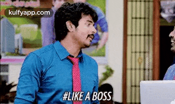 a man in a blue shirt and pink tie is talking to another man .