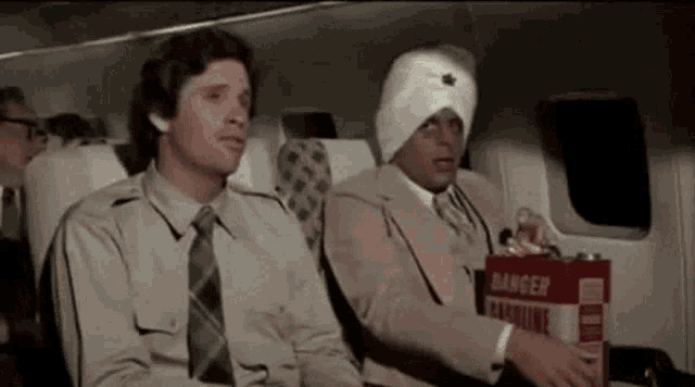 two men are sitting on a plane with a can of gasoline in their hand .