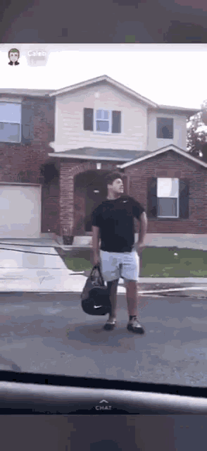 a man carrying a nike duffel bag is standing in front of a house