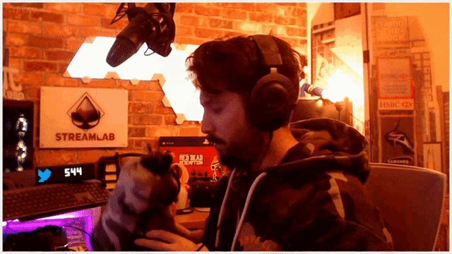 a man wearing headphones playing a video game with a streamlab sign behind him