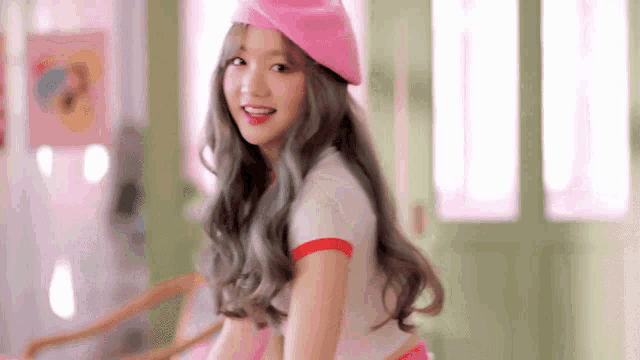 a young woman wearing a pink beret and a pink shirt is sitting on a chair .