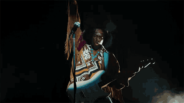 a man playing a guitar in front of a microphone