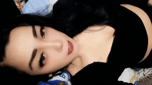 a woman is laying on a bed wearing a black bra and looking at the camera .