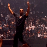 a man in a black shirt is dancing in front of a crowd of people