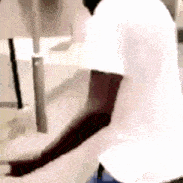a man in a white t-shirt is standing in front of a sink .