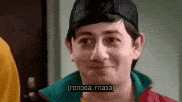 a man wearing a hat and a jacket is making a funny face while talking in a foreign language .