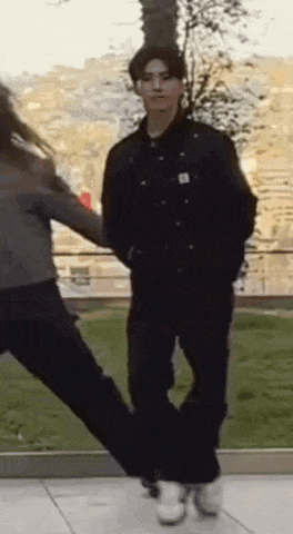 a man and a woman are dancing in a park .