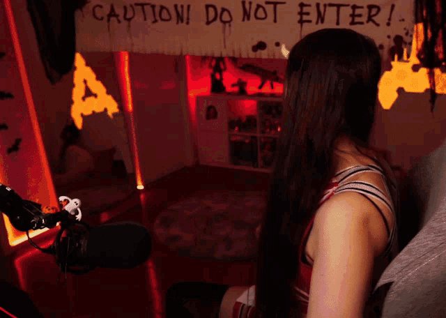 a woman is sitting in front of a sign that says caution do not enter