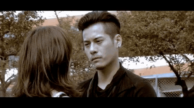 a man and a woman are looking at each other in a park