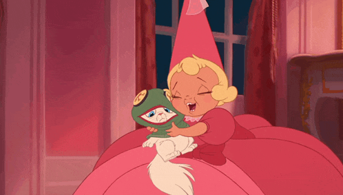 a little girl in a pink dress is hugging a cat with a hat on