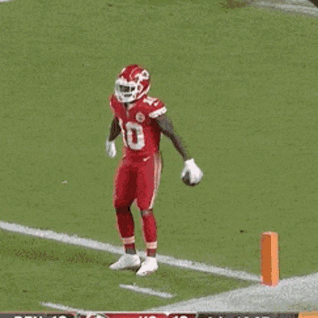 a football player wearing a red jersey and white pants is running on the field