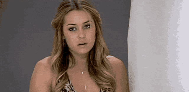a woman in a bikini is making a funny face while standing in front of a white curtain .
